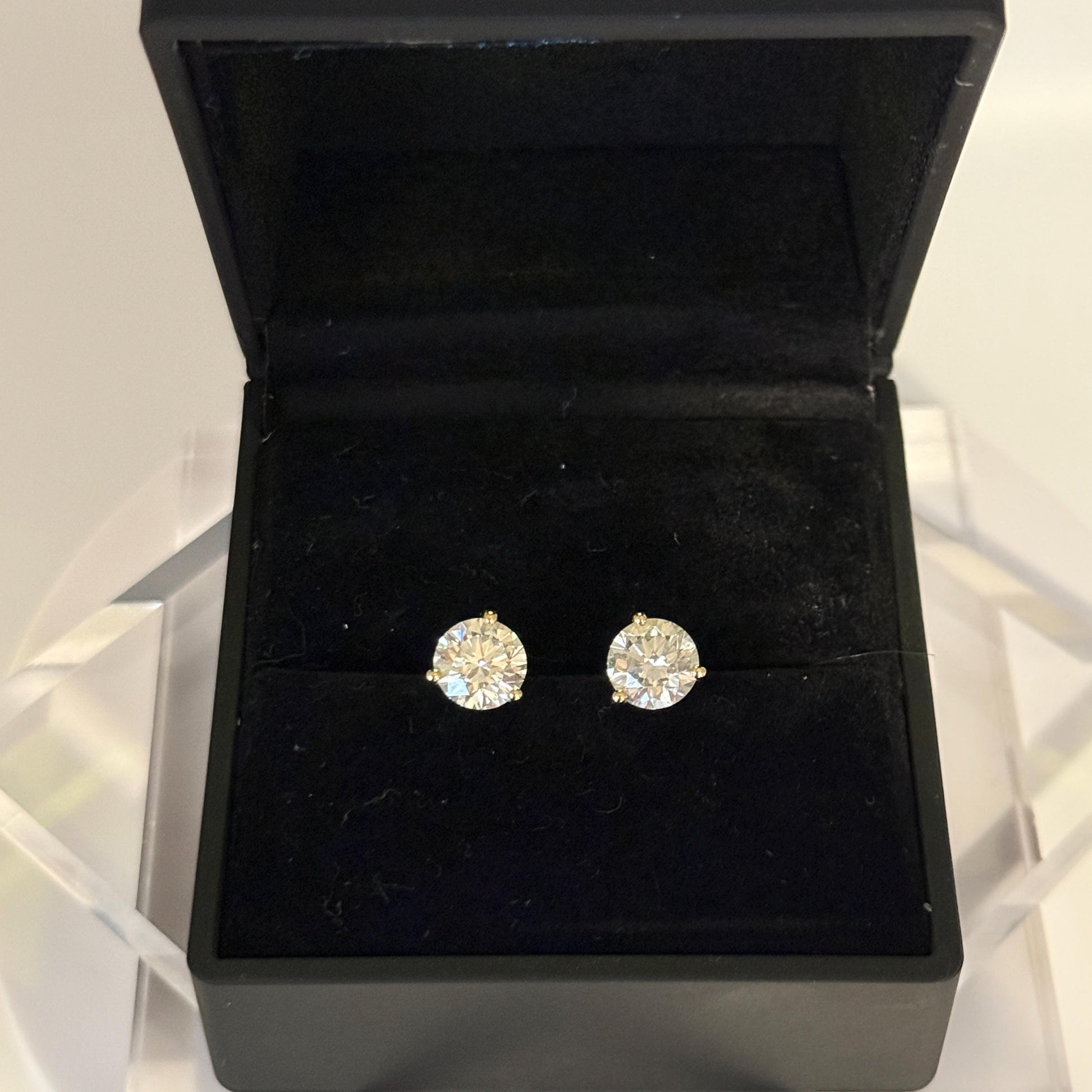 Close-up of 2 carat lab grown diamond stud earrings set in solid 14K gold, round cut, minimalist design on white background.
