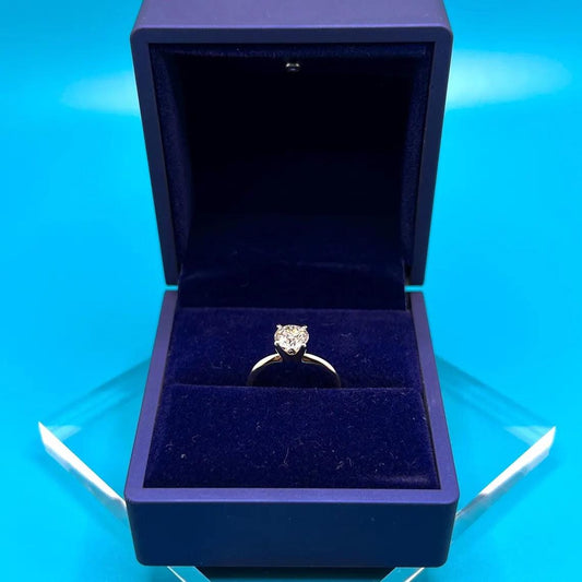 Close-up of a 1 carat round lab grown diamond engagement ring set in 14K gold solitaire setting, shown on a neutral background.