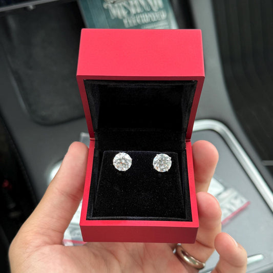 Close-up of 6 carat lab grown diamond stud earrings set in solid 14K gold, round cut, minimalist design on white background.