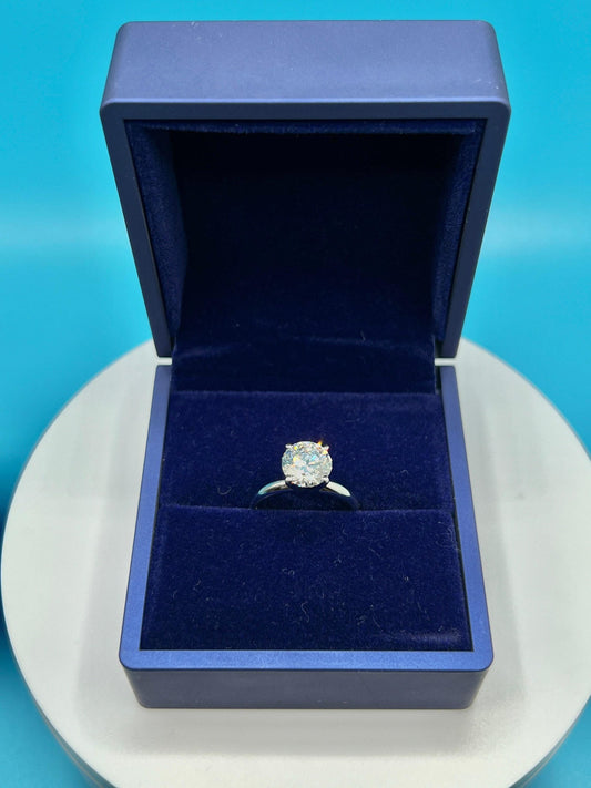 Close-up of a 2 carat round lab grown diamond engagement ring set in 14K gold solitaire setting, shown on a neutral background.
