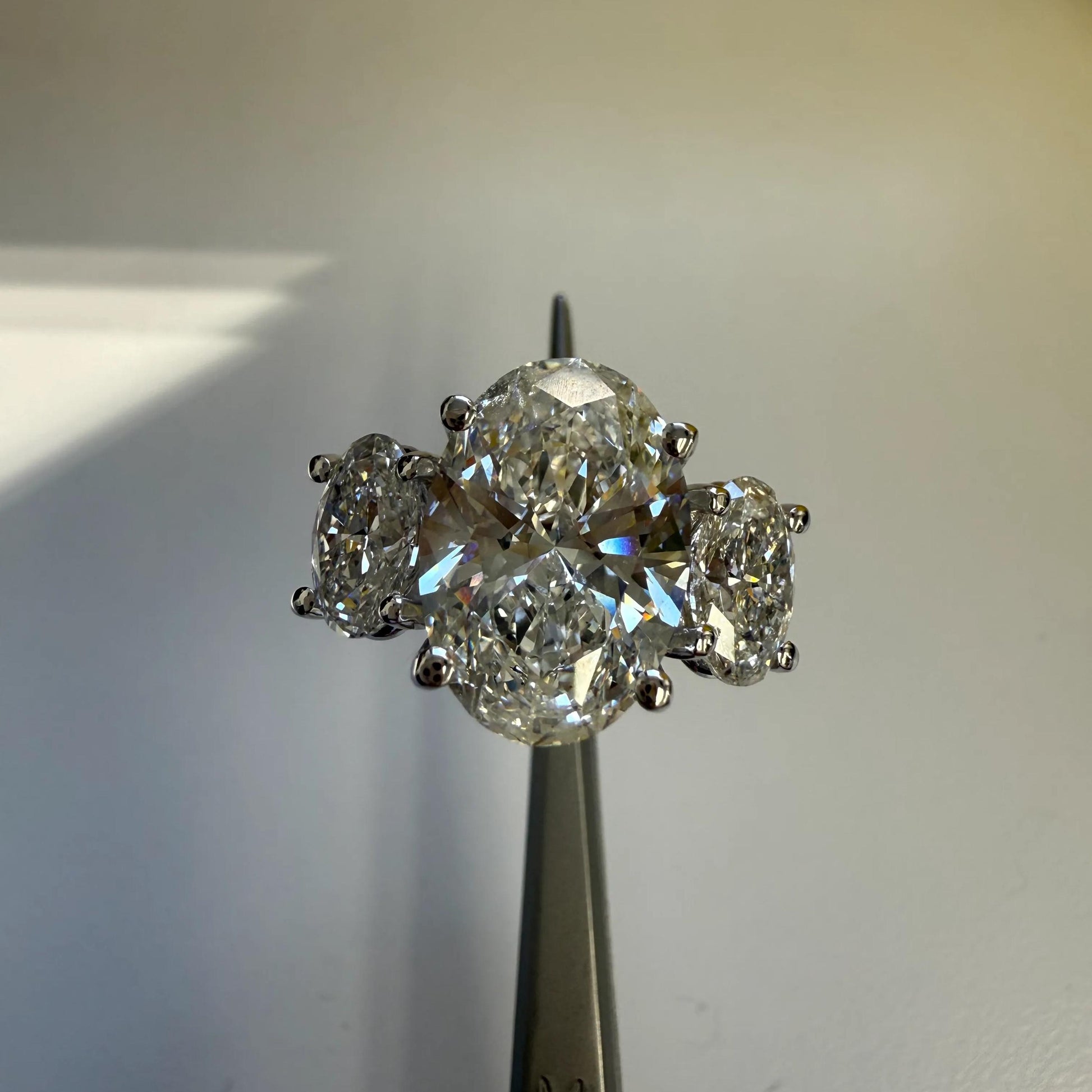 A close-up image of a diamond ring with a large central diamond surrounded by smaller diamonds, displayed on a metal object.