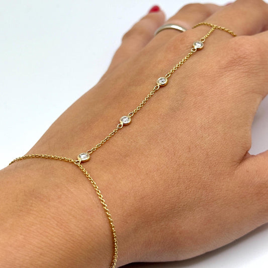 14k gold hand chain featuring four bezel-set lab-grown diamonds connecting a delicate finger ring to a gold bracelet, worn on a woman's hand