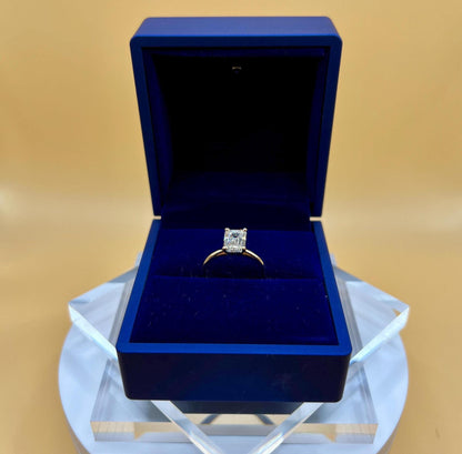 Close-up of 4 carat emerald cut lab grown diamond solitaire engagement ring in solid 14K gold, photographed on a soft background.