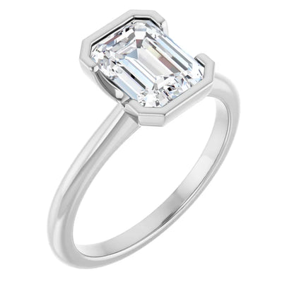 A silver engagement ring with a large, clear emerald cut diamond set in the center.