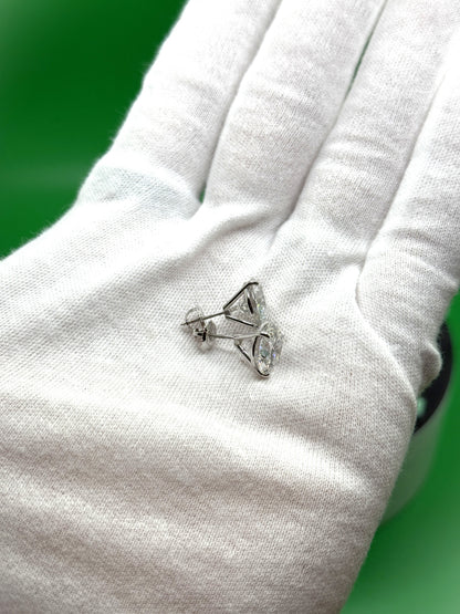A close-up image of a person's hand wearing a white glove, holding a small silver earring with a clear gemstone.