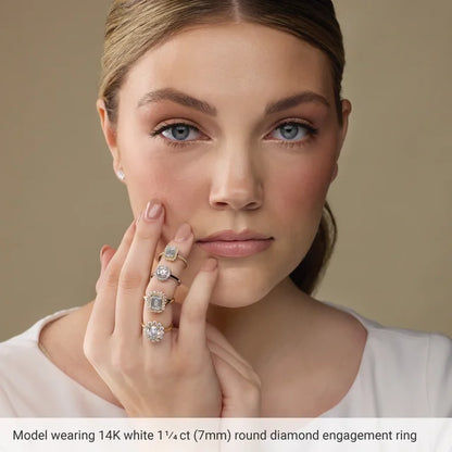 A woman wearing a 14K white 1/4ct (7mm) round diamond engagement ring is shown in the image.