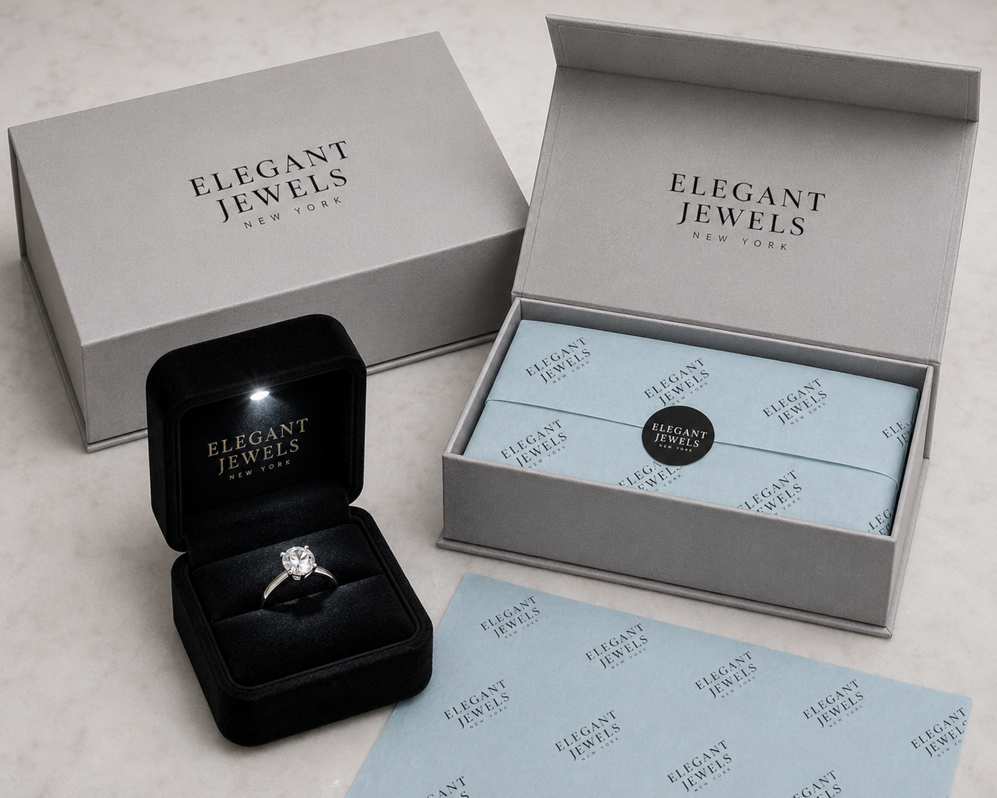 a collection of jewelry-related items, including a black jewelry box containing a diamond ring, two open boxes with the brand name "Elegant Jewels" printed on them, and some wrapping paper with the same branding.