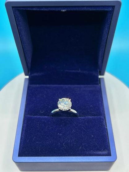 A diamond engagement ring is displayed in a blue jewelry box against a blue background.