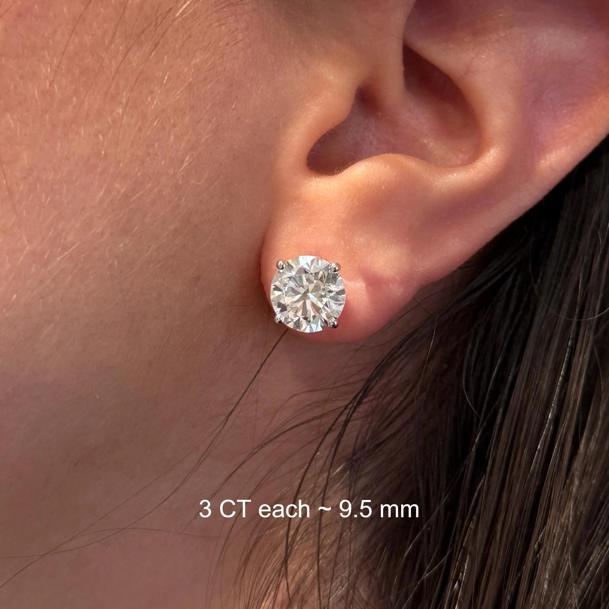 A close-up of a person's ear with a large, clear diamond earring.