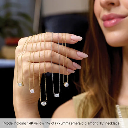 A woman is holding up a necklace with multiple diamond pendants, including a yellow 1/6th (1/6) carat emerald diamond 18-inch necklace.