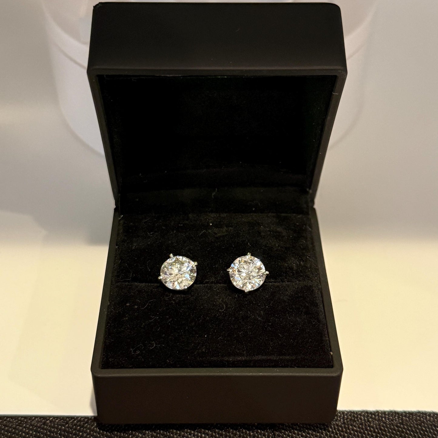 Close-up of 4 carat lab grown diamond stud earrings set in solid 14K gold, round cut, minimalist design on white background.