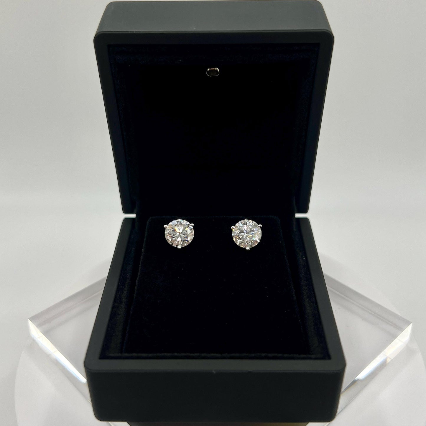 Close-up of 3 carat lab grown diamond stud earrings set in solid 14K gold, round cut, minimalist design on white background.