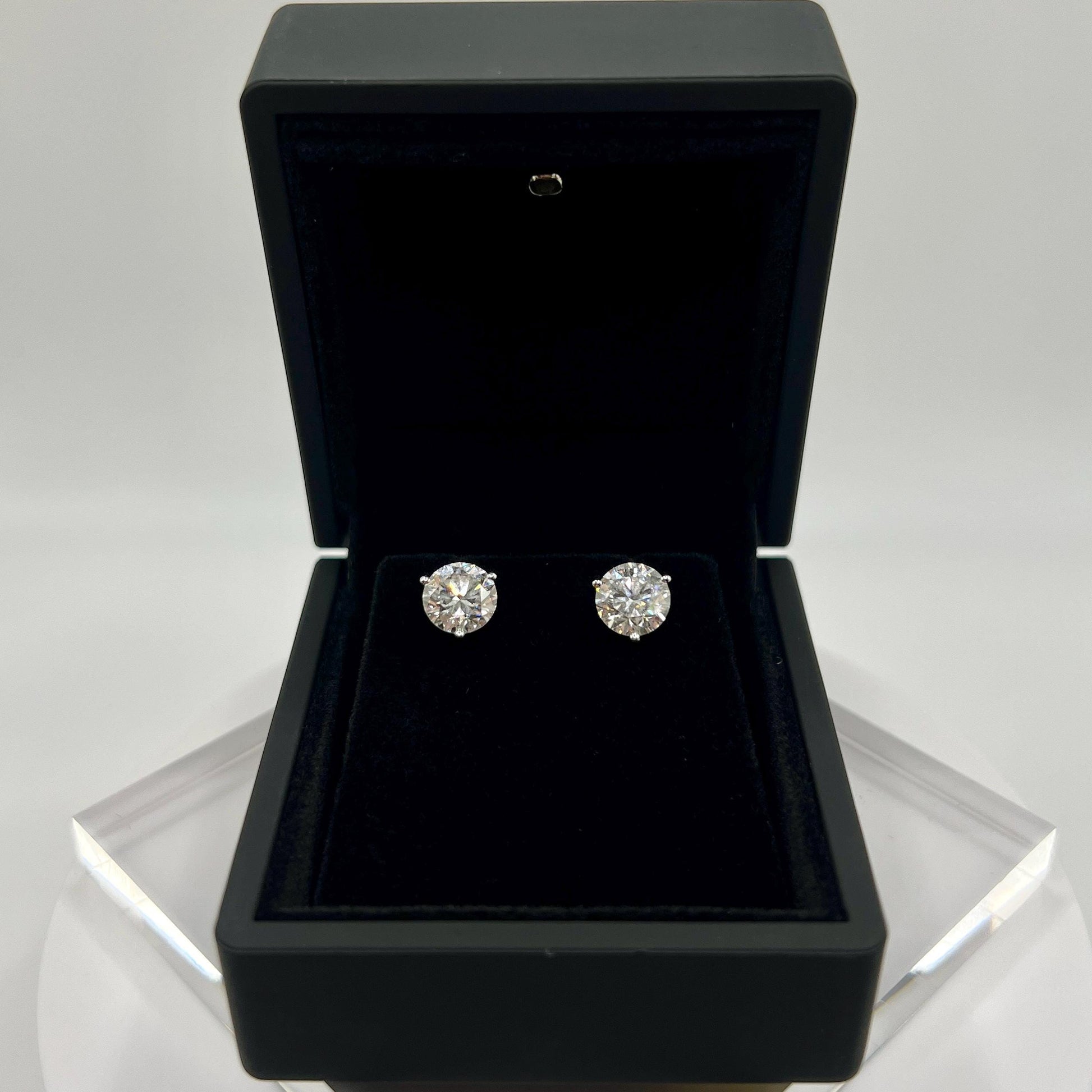 Close-up of 3 carat lab grown diamond stud earrings set in solid 14K gold, round cut, minimalist design on white background.