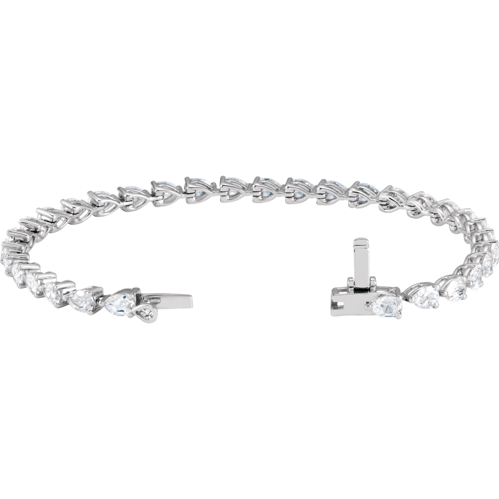A silver bracelet with a row of small diamonds or pearls on it, set against a dark blue background.