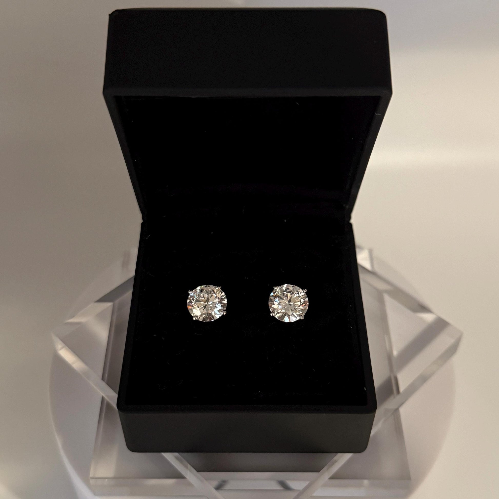 Close-up of 5 carat lab grown diamond stud earrings set in solid 14K gold, round cut, minimalist design on white background.