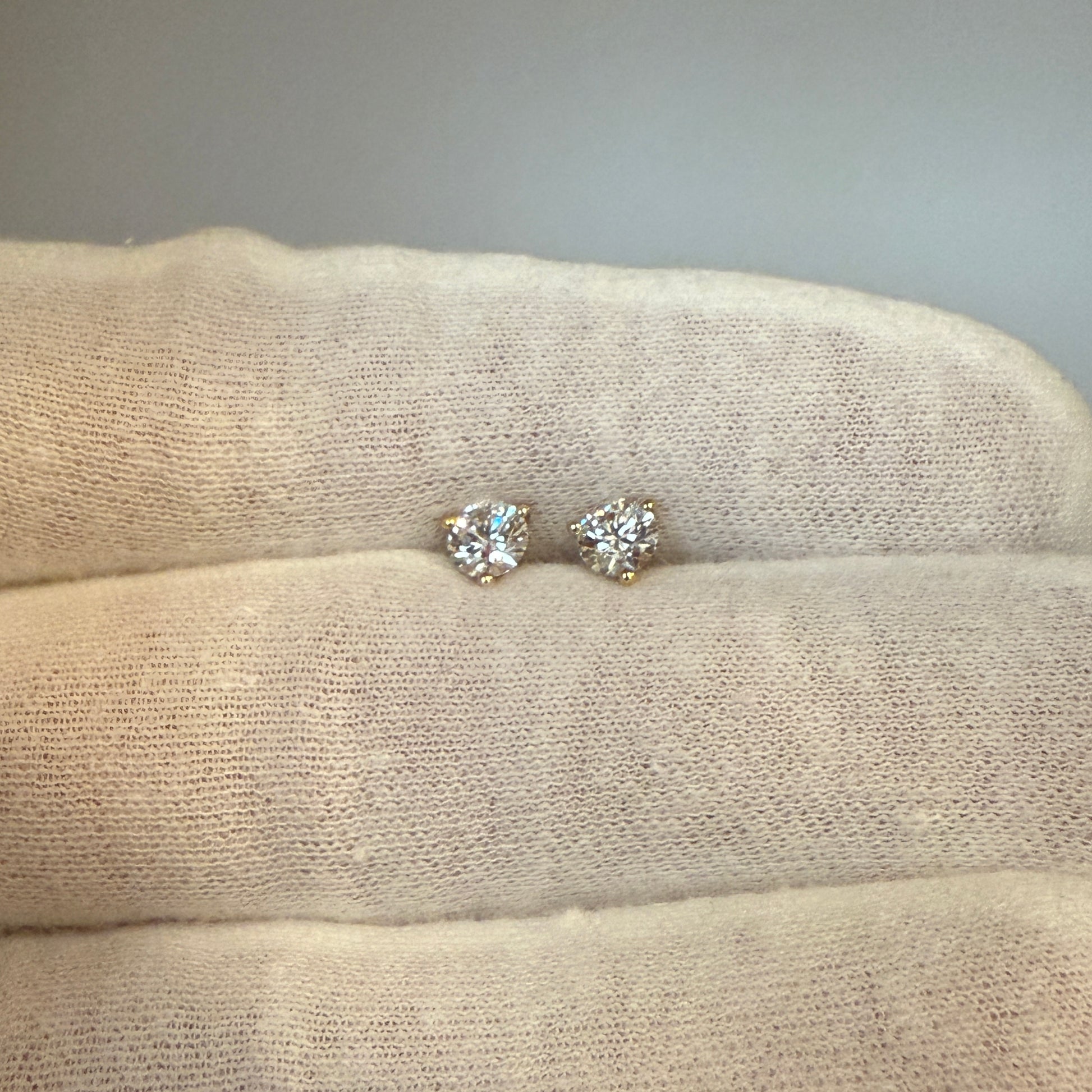 A pair of diamond earrings resting on a soft, textured fabric.