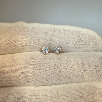 A pair of diamond earrings resting on a soft, textured fabric.