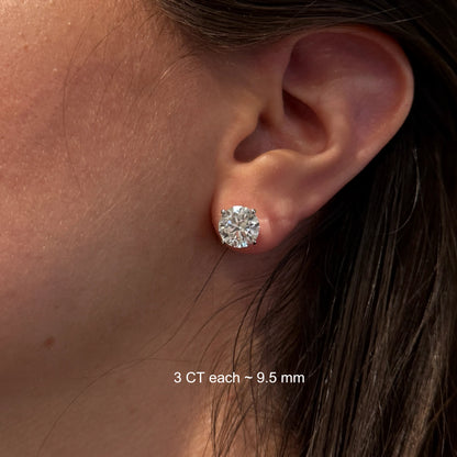 A close-up of a person's ear with a large, clear diamond earring in the earlobe.