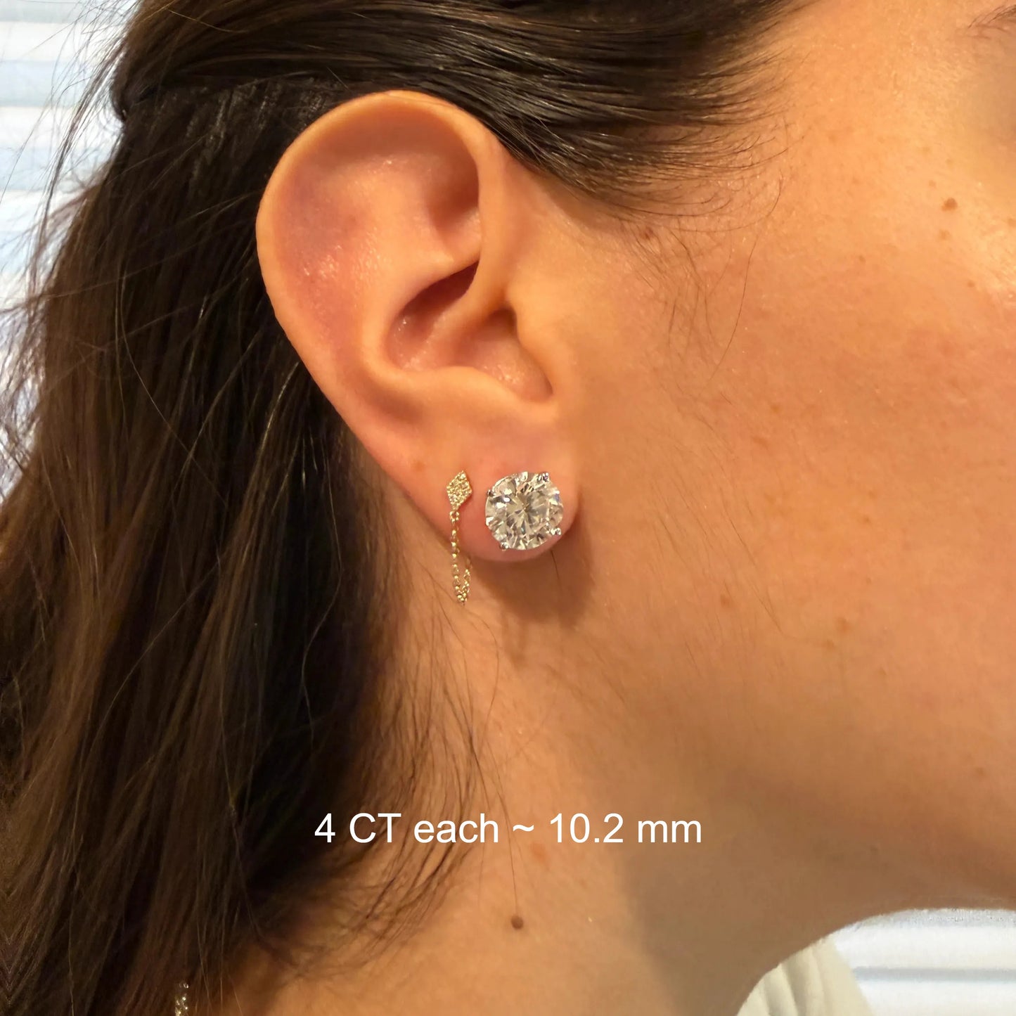 A close-up view of a person's ear adorned with a large, sparkling diamond earring.