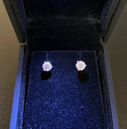 A pair of diamond earrings displayed in a black jewelry box.